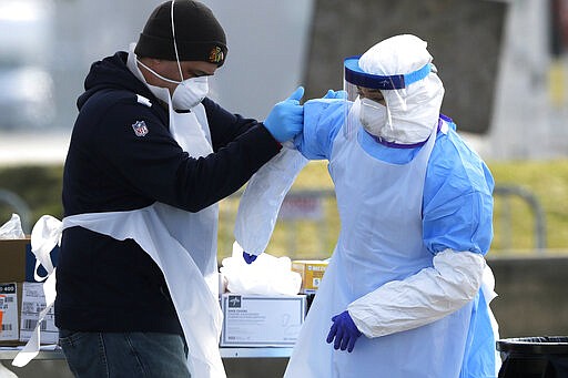 Medical personnel help each other at a federal COVID-19 drive-thru testing site in the parking lot of Walmart in North Lake, Ill., Wednesday, March 25, 2020. The new coronavirus cause mild or moderate symptoms for most people, but for some, especially older adults and people with existing health problems, it can cause more severe illness or death. (AP Photo/Nam Y. Huh)