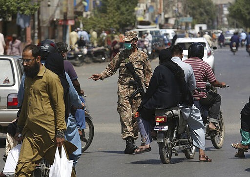 A Pakistani soldiers stops vehicles to implement a lockdown in an effort to contain the coronavirus, in Karachi, Pakistan, Tuesday, March 24, 2020. Pakistani authorities said they'd shut down train operations across the country from Wednesday until March 31 in an effort to contain the spread of the virus. (AP Photo/Fareed Khan)