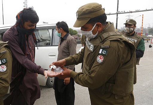 A police officers dispenses hand sanitizer in an effort to contain the coronavirus, in Lahore, Pakistan, Tuesday, March 24, 2020. Pakistani authorities said they'd shut down train operations across the country from Wednesday until March 31 in an effort to contain the spread of the virus. (AP Photo/K.M. Chaudhry)