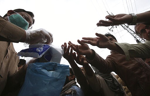 People buy gloves to avoid the spread of coronavirus outbreak in Peshawar, Pakistan, Tuesday, March 24, 2020. Pakistani authorities said they'd shut down train operations across the country from Wednesday until March 31 in an effort to contain the spread of the virus. (AP Photo/Muhammad Sajjad)