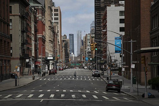 FILE - In this March 22, 2020, file photo, a cyclist rides his bicycle down the middle of a main road in downtown New York. World War II references are now heard daily, not because another momentous 75th anniversary, Victory in Europe Day approaches in May but because of the coronavirus. (AP Photo/Wong Maye-E, File)