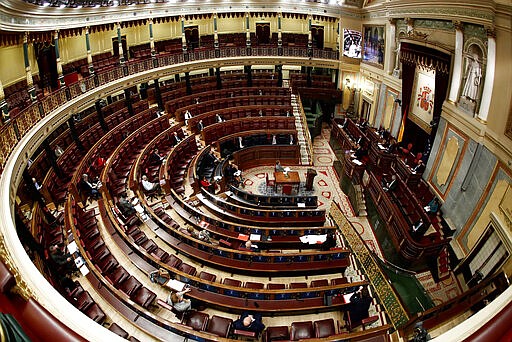 Spain's Prime Minister Pedro Sanchez, right, speaks in a nearly empty parliament while the majority of lawmakers follow the session online before a vote to approve the extension of the national lockdown in Madrid, Spain, Wednesday, March 25, 2020. Spain released new figures of the official number of deaths in Spain because of the COVID-19 coronavirus, surpassing China's death toll. The new coronavirus causes mild or moderate symptoms for most people, but for some, especially older adults and people with existing health problems, it can cause more severe illness or death. (Mariscal, Pool photo via AP)