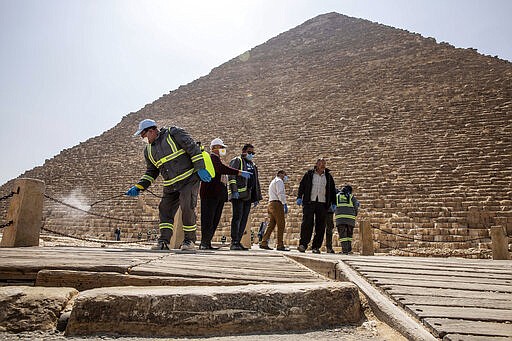 Municipal workers sanitize the walkways around the Giza pyramid complex in hopes of curbing the spread of the new coronavirus outbreak in Egypt, Wednesday, March 25, 2020. The new coronavirus causes mild or moderate symptoms for most people, but for some, especially older adults and people with existing health problems, it can cause more severe illness or death. (AP Photo/Nariman El-Mofty)