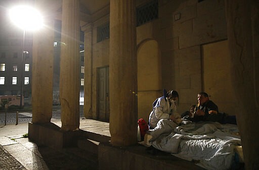 A volunteer nurse wearing a mask tends to homeless in Milan, Tuesday, March 24, 2020. The new coronavirus causes mild or moderate symptoms for most people, but for some, especially older adults and people with existing health problems, it can cause more severe illness or death. (AP Photo/Antonio Calanni)