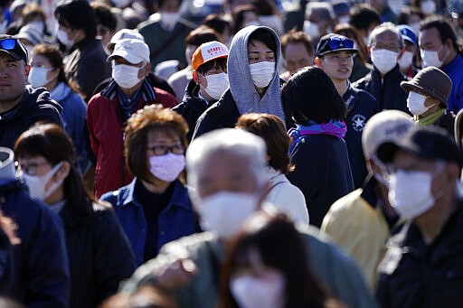 Spectators wait to see the Olympic flame display ceremony in Iwaki, Fukushima Prefecture, northern Japan, Wednesday, March 25, 2020. IOC President Thomas Bach has agreed &quot;100%&quot; to a proposal of postponing the Tokyo Olympics for about one year until 2021 because of the coronavirus outbreak, Japanese Prime Minister Shinzo Abe said Tuesday. (AP Photo/Eugene Hoshiko)