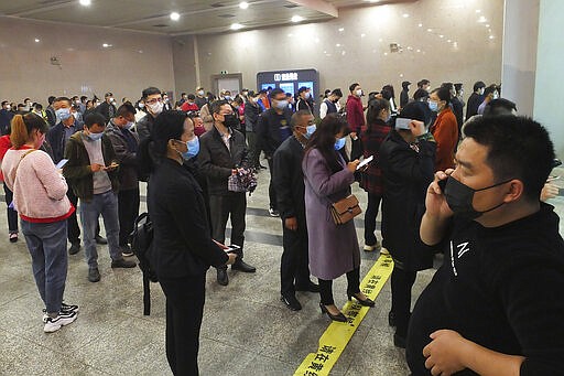 Travelers wearing masks line up to buy train tickets at a railway station in Yichang in central China's Hubei province Wednesday, March 25, 2020. Trains carrying factory employees back to work after two months in locked-down cities rolled out of Hubei province, the center of China's virus outbreak, as the government on Wednesday began lifting the last of the controls that confined tens of millions of people to their homes. (Chinatopix via AP)