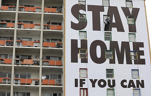 A billboard is installed on an apartment building in Cape Town, South Africa, Wednesday, March 25, 2020, before the country of 57 million people, will go into a nationwide lockdown for 21 days from Thursday to fight the spread of the new coronavirus. The new coronavirus causes mild or moderate symptoms for most people, but for some, especially older adults and people with existing health problems, it can cause more severe illness or death. (AP Photo/Nardus Engelbrecht)