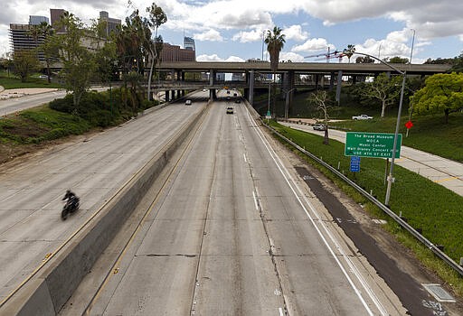 A motorcyclist rides in extremely light traffic along California 110 in Los Angeles on Tuesday, March 24, 2020. California Gov. Gavin Newsom is ordering the state's 40 million residents to stay at home indefinitely. His order restricts non-essential movements to control the spread of the coronavirus that threatens to overwhelm the state's medical system. He called up 500 National Guard troops Thursday to help with distributing food. (AP Photo/Damian Dovarganes)