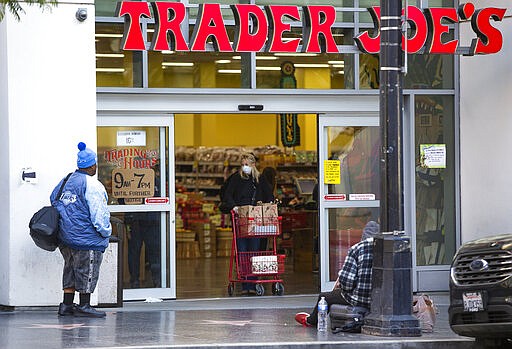 A person waits to enter a Trader Joe's grocery store, as a shopper leaves in the Hollywood section of Los Angeles on Tuesday, March 24, 2020. (AP Photo/Damian Dovarganes)