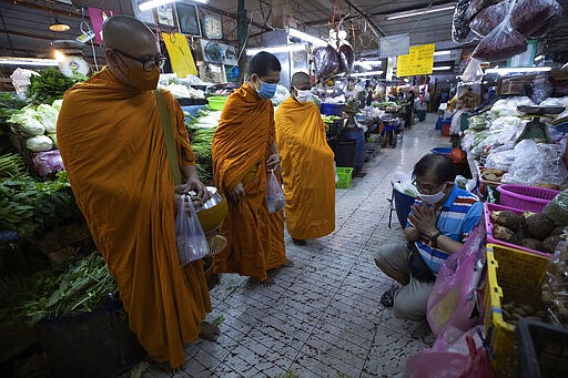 A Thai Buddhist prays after offering food to Thai Buddhist monks as they wear face masks to protect themselves from a new coronavirus in Bangkok, Thailand, Wednesday, March 25, 2020. Thailand's government agreed to declare an emergency to take stricter measures to control the coronavirus outbreak that has infected hundreds of people in the Southeast Asian country. For most people, the new coronavirus causes mild or moderate symptoms, such as fever and cough that clear up in two to three weeks. For some, especially older adults and people with existing health problems, it can cause more severe illness, including pneumonia and death. (AP Photo/Sakchai Lalit)