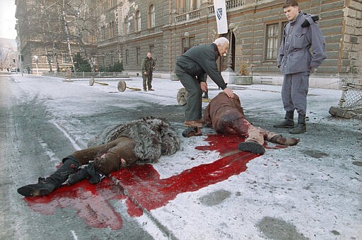 FILE - In this  Jan. 30, 1993 file photo, Bosnian soldiers help injured people laying on the street in front of the Bosnian presidency after a shell hit the crowded street in Sarajevo. Western countries are reeling from the coronavirus pandemic, awakening to a new reality of economic collapse, overwhelmed hospitals and home confinement. But for millions across the Middle East and in conflict zones elsewhere, much of this is familiar.  (AP Photo/Hansi Krauss, File)