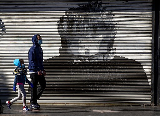 Pedestrians wear face masks as they walk on Hollywood Boulevard in Los Angeles, Tuesday, March 24, 2020. New cases of the new coronavirus surged around the state. (AP Photo/Damian Dovarganes)