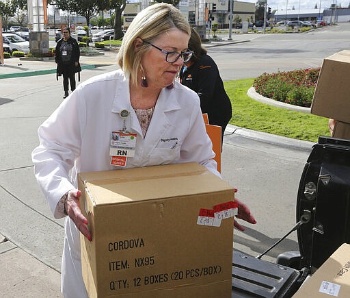 In this Monday, March 23, 2020, photo Chief Nursing Officer Terri Church helps unload donated masks at the Dignity Health Mercy and Memorial Hospitals in Bakersfield, Calif. The Tejon Indian Tribe donated 1,400 N95 particulate masks from the Tejon Indian Tribe Health Services to Dignity Health Mercy and Memorial Hospitals. (Alex Horvath/The Californian via AP)