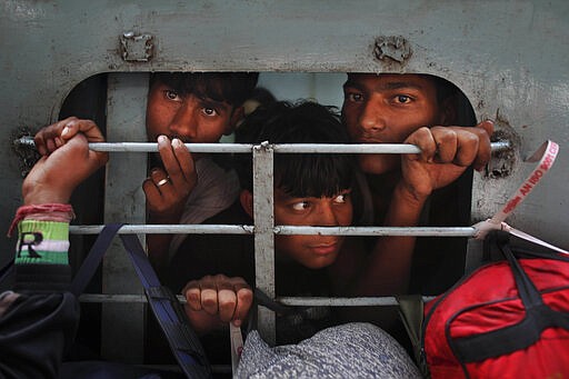 FILE - In this Nov. 16, 2012, file photo, Indians look out from an overcrowded train to travel home for the Chhath Puja festival dedicated to the Sun God, at a railway station in New Delhi, India, Friday. India's colossal passenger railway system has come to a halt Sunday, March 22, 2020, as officials take emergency measures to keep the coronavirus pandemic from spreading in the country of 1.3 billion. The railway system is often described as India's lifeline, transporting 23 million people across the vast subcontinent each day, some 8.4 billion passengers each year. (AP Photo/Kevin Frayer)