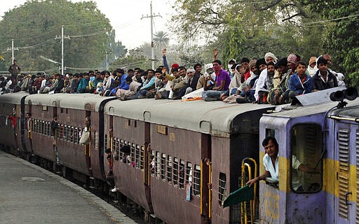 FILE - In this Tuesday, Feb. 21, 2012, file photo, Indian Hindu devotees sit on the roof of a train as they leave after attending Shivratri festival fair at Bhavnath temple in Junagadh, 327 kilometers (204 miles) from Ahmadabad, India. India's colossal passenger railway system has come to a halt Sunday, March 22, 2020, as officials take emergency measures to keep the coronavirus pandemic from spreading in the country of 1.3 billion. The railway system is often described as India's lifeline, transporting 23 million people across the vast subcontinent each day, some 8.4 billion passengers each year.  (AP Photo/Ajit Solanki, File)