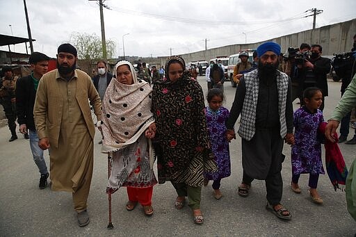 Family members walk through the site of an attack in Kabul, Afghanistan, Wednesday, March 25, 2020. Gunmen stormed a religious gathering of Afghanistan's minority Sikhs in their place of worship in the heart of the Afghan capital's old city on Wednesday, a minority Sikh parliamentarian said. (AP Photo/Rahmat Gul)