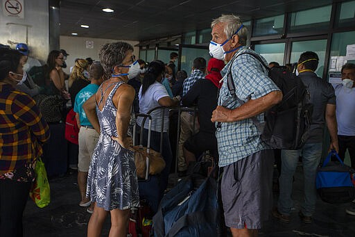 Travelers wait for a charter flight coordinated by the U.S. embassy at the La Aurora airport in Guatemala City, Tuesday, March 24, 2020. American citizens stranded abroad because of the coronavirus pandemic are seeking help in returning to the United States. (AP Photo/Moises Castillo)