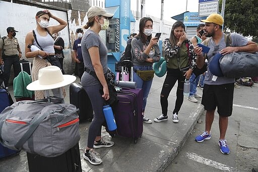 Tourists from the United States wait outside the closed Jorge Chavez International Airport for a member of the U.S. Embassy to escort them to a flight that will fly them back to the U.S., in Callao Peru, Friday, March 20, 2020, on the fifth day of a state of emergency decreed by the government to prevent the spread of the new coronavirus.  (AP Photo/Martin Mejia)