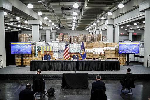 In this March 24, 2020, photo New York Gov. Andrew Cuomo, center, speaks while practicing social distancing against a backdrop of medical supplies during a news conference at the Jacob Javits Center that will house a temporary hospital in response to the COVID-19 outbreak in New York. (AP Photo/John Minchillo)