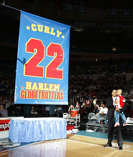 FILE - In this Feb. 15, 2008, file photo, Harlem Globetrotters' Fred &quot;Curly&quot; Neal looks on with his grandson Jaden Neal-Roberts as his No. 22 is retired by the world renowned Harlem Globetrotters at Madison Square Garden in New York. Neal, the dribbling wizard who entertained millions with the Harlem Globetrotters for parts of three decades, has died the Globetrotters announced Thursday, March 26, 2020. He was 77. Neal played for the Globetrotters from 1963-85, appearing in more than 6,000 games in 97 countries for the exhibition team known for its combination of comedy and athleticism. (AP Photo/Frank Franklin II, File)