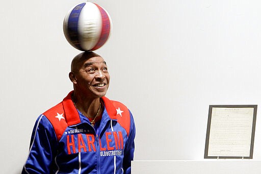 FILE - In this Dec. 10, 2010, file photo, Harlem Globetrotters Fred &quot;Curly&quot; Neal spins a ball on his head prior to the bidding for the Naismith Rules, the original rules for basketball, framed at right, at Sotheby's in New York. Neal, the dribbling wizard who entertained millions with the Harlem Globetrotters for parts of three decades, has died the Globetrotters announced Thursday, March 26, 2020. He was 77. Neal played for the Globetrotters from 1963-85, appearing in more than 6,000 games in 97 countries for the exhibition team known for its combination of comedy and athleticism. (AP Photo/Richard Drew, File)