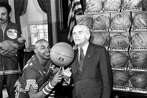 FILE - In this Feb. 15, 1977, file photo, the Harlem Globetrotters' Fred &quot;Curly&quot; Neal of shows New York City Mayor Abe Beame the art of balancing a basketball on a finger during ceremony at City Hall. Neal, the dribbling wizard who entertained millions with the Harlem Globetrotters for parts of three decades, has died the Globetrotters announced Thursday, March 26, 2020. He was 77. Neal played for the Globetrotters from 1963-85, appearing in more than 6,000 games in 97 countries for the exhibition team known for its combination of comedy and athleticism. (AP Photo/File)