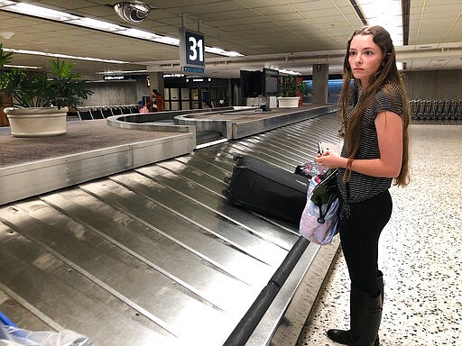 Destiny Rohrer, a 20-year-old Navy sailor, waits for her bag at Honolulu's Daniel K. Inouye International Airport on Thursday, March 26, 2020, as the state of Hawaii imposed a 14-day traveler quarantine to slow the spread of coronavirus. Travelers landed in Hawaii to a new requirement that they hole up in hotel rooms or their homes for 14 days. (AP Photo/Audrey McAvoy)