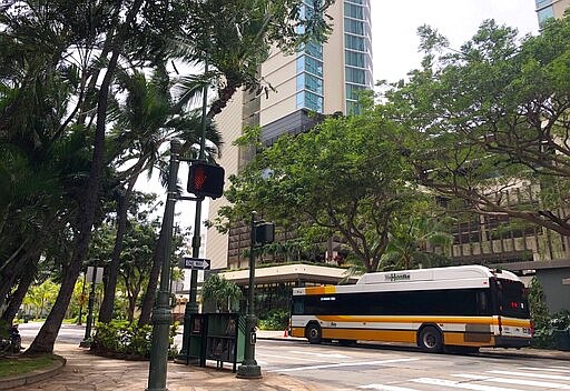 A city bus is parked on an empty street in the Waikiki neighborhood of Honolulu, Thursday, March 26, 2020. A 14-day quarantine on travelers takes effect in Hawaii, one of the world's most famous tourist destinations, as the island state fights the coronavirus. Hawaii welcomed 10 million travelers last year, for an average of about 830,000 a month. Authorities expect this number will dwindle to nearly zero in April as the new rule is implemented. Dozens of hotels are temporarily shutting their doors in response. (AP Photo/Caleb Jones)