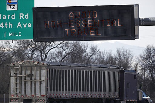 A tractor-trailer heads westbound on Interstate 70 near the Ward Road exit as a message flashes on the travel board as a statewide stay-at-home order takes effect to reduce the spread of the new coronavirus Thursday, March 26, 2020, in Wheat Ridge, Colo. The new coronavirus causes mild or moderate symptoms for most people, but for some, especially older adults and people with existing health problems, it can cause more severe illness or death. (AP Photo/David Zalubowski)