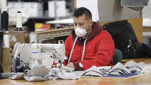 A worker sews face masks at SugarHouse Industries Thursday, March 26, 2020, in Midvale, Utah. SugarHouse Industries, a Utah company that usually manufactures boat tops and covers, has reconfigured its operation amid the spread of the coronavirus to produce face shields and masks. (AP Photo/Rick Bowmer)