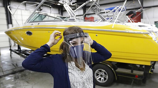 Romy Humphries wears a face mask and face shield at SugarHouse Industries Thursday, March 26, 2020, in Midvale, Utah. SugarHouse Industries, a Utah company that usually manufactures boat tops and covers, has reconfigured its operation amid the spread of the coronavirus to produce face shields and masks. (AP Photo/Rick Bowmer)