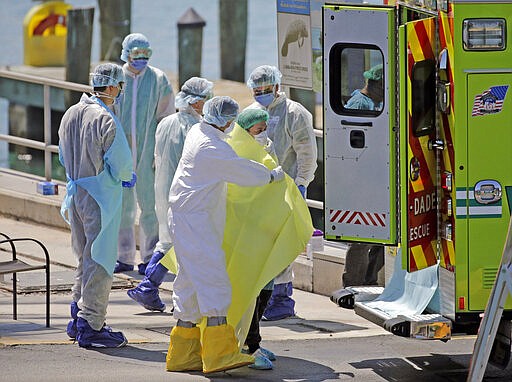 First responders care for crew members as they arrive by lifeboats from the cruise ship Costa Magica during the coronavirus outbreak at the U.S. Coast Guard Station Miami Beach, Thursday, March 26, 2020, in Miami Beach, Fla. The ship remained off shore. (David Santiago/Miami Herald via AP)