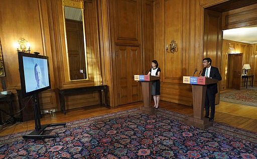 In this image made available by British government because no media allowed into 10 Downing Street because of the coronavirus pandemic, showing Chancellor of the Exchequer Rishi Sunak, right, holding a digital press conference about the COVID-19 coronavirus, with Deputy Chief Medical Officer Doctor Jenny Harries, centre, inside 10 Downing Street, London, Thursday March 26, 2020.  Sunak on Thursday announced measures to give financial help to self-employed people. (Pippa Fowles/10 Downing Street via AP)