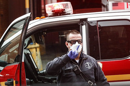 An FDNY medical worker wears personal protective equipment outside a COVID-19 testing site at Elmhurst Hospital Center, Wednesday, March 25, 2020, in New York. Gov. Andrew Cuomo sounded his most dire warning yet about the coronavirus pandemic Tuesday, saying the infection rate in New York is accelerating and the state could be as close as two weeks away from a crisis that sees 40,000 people in intensive care. Such a surge would overwhelm hospitals, which now have just 3,000 intensive care unit beds statewide. (AP Photo/John Minchillo)