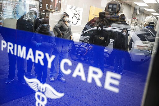 Patients wait inside an urgent care pharmacy while wearing personal protective equipment, Wednesday, March 25, 2020, in the Queens borough of New York. Gov. Andrew Cuomo sounded his most dire warning yet about the coronavirus pandemic Tuesday, saying the infection rate in New York is accelerating and the state could be as close as two weeks away from a crisis that sees 40,000 people in intensive care. Such a surge would overwhelm hospitals, which now have just 3,000 intensive care unit beds statewide. (AP Photo/John Minchillo)