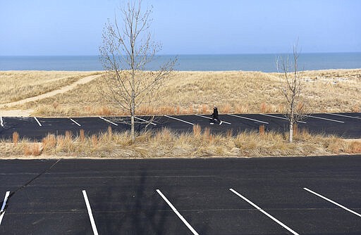 A woman walks along Jean Klock Park in Benton Harbor, Mich., Wednesday, March 25, 2020. A &quot;Stay Home, Stay Safe&quot; Executive Order is currently in effect in Michigan forcing all non-critical businesses and operations to temporarily remain closed and for residents to stay at home and six feet away from others. (Don Campbell/The Herald-Palladium via AP)