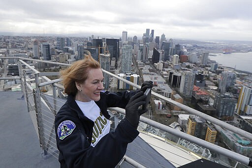 Seattle Mayor Jenny Durkan takes photos from the roof of the Space Needle, Thursday, March 26, 2020, in Seattle before raising a flag that reads &quot;#We Got This Seattle.&quot; Durkan said the flag is intended to be a symbol of unity and encouragement as the city faces a state-wide stay-at-home mandate and one of the worst outbreaks of the new coronavirus in the U.S. The flag will fly from the Space Needle, which is closed to visitors, for at least several weeks. (AP Photo/Ted S. Warren)