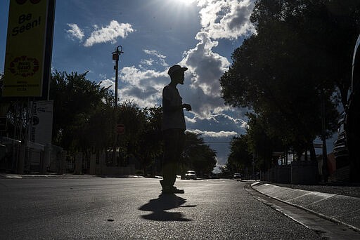 A parking guard stands in the deserted Vilakazi street in the township of Soweto, near Johannesburg, South Africa, Thursday March 26, 2020, just hours before South Africa goes into a nationwide lockdown for 21 days in an effort to mitigate the spread to the coronavirus. The new coronavirus causes mild or moderate symptoms for most people, but for some, especially older adults and people with existing health problems, it can cause more severe illness or death.(AP Photo/Jerome Delay)