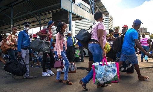 People wearing face masks to protect against coronavirus, walk at a taxi rank in Johannesburg, South Africa, Thursday, March 26, 2020. It is just hours before South Africa goes into a nationwide lockdown for 21-days in an effort to mitigate the spread to the coronavirus. (AP Photo/Themba Hadebe)