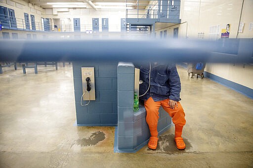 FILE - In this Nov. 15, 2019, file photo, a detainee talks on the phone in his pod at the Stewart Detention Center in Lumpkin, Ga. While much of daily life has ground to a halt to reduce the spread of the coronavirus, the Trump administration is resisting calls from immigration judges and attorneys to stop in-person hearings and shutter all immigration courts. They say the most pressing hearings can still be done by phone so immigrants aren't stuck in detention indefinitely. (AP Photo/David Goldman, File)