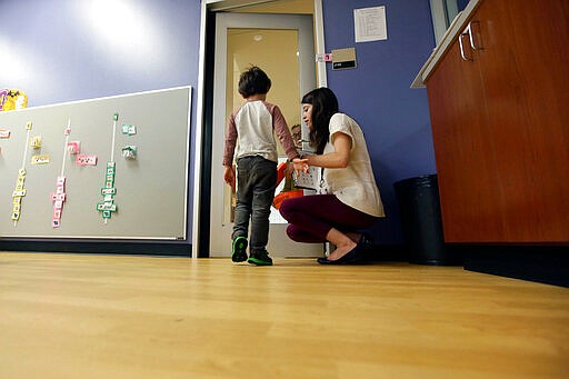 FILE - In this Monday, Oct. 24, 2016 file photo, Megan Krail helps a 4-year-old boy with Autism Spectrum Disorder practice trick-or-treating at The University of Texas at Dallas' Callier Center for Communication Disorders preschool class in Dallas. According to a report released by the Centers for Disease Control and Prevention on Thursday, March 26, 2020, about 1 in 54 U.S. children were identified as having autism in 2016. That's up from 1 in 59 children in 2014, and from 1 in 68 children in both 2010 and 2012. The study focused on 8-year-old children. (AP Photo/LM Otero)