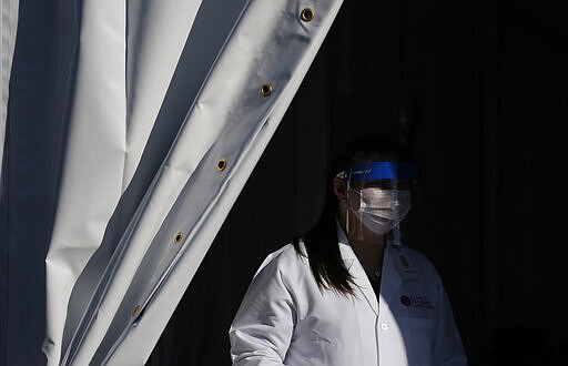 A worker with Clinical Pathology Laboratories waits for patients at a drive-through coronavirus testing site Tuesday, March 24, 2020, in Las Vegas. UNLV Medicine, the clinical arm of the UNLV School of Medicine, started conducting COVID-19 testing by appointment for people who meet the Centers for Disease Control and Prevention guidelines. (AP Photo/John Locher)