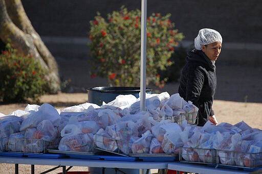 A worker prepares bags of food at a high school Thursday, March 26, 2020, in Las Vegas. The Clark County School district is distributing food to students at schools closed due to coronavirus. (AP Photo/John Locher)