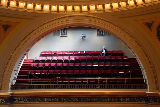 State Sen. John Marty waits in the gallery for the start of the Minnesota State Senate which met Thursday, March 26, 2020 at the State Capitol in St. Paul, Minn. to take up bills related to the coronavirus in the state. Due to social distancing, the gallery and other rooms were used for the lawmakers with the Senate floor limited to members. The new coronavirus causes mild or moderate symptoms for most people, but for some, especially older adults and people with existing health problems, it can cause more severe illness or death. (AP Photo/Jim Mone)