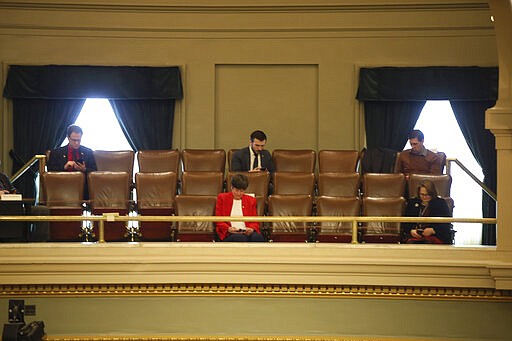 Several Lawmakers in the Minnesota House practice social distancing from a gallery Thursday, March 26, 2020 at the State Capitol in St. Paul, Minn. as representatives met to take up bills related to the coronavirus in the state. A limited number of members were allowed on the House floor. The new coronavirus causes mild or moderate symptoms for most people, but for some, especially older adults and people with existing health problems, it can cause more severe illness or death. (AP Photo/Jim Mone)