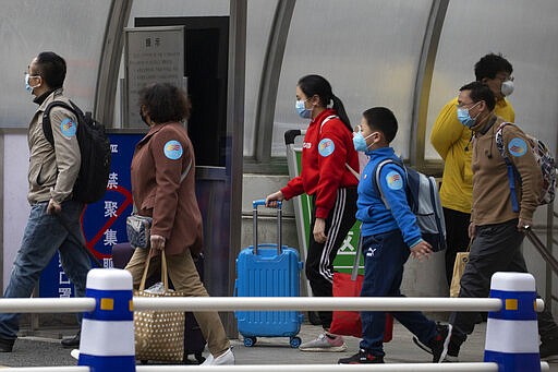 Returnees from the Hubei Province leave from the West Train Station to board buses in Beijing on Thursday, March 26, 2020. China is allowing people who were under lockdown in Hubei to leave the province at the center of the coronavirus outbreak now sweeping the globe. In the nation's capital, authorities are accepting about 800 people a day from Hubei. (AP Photo/Ng Han Guan)