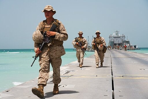 U.S. Marines walk down a removable Trident Pier leading to an American ship docked near an Emirati military base home to a Military Operations and Urban Terrain facility in al-Hamra, United Arab Emirates, Monday, March 23, 2020. U.S. Marines and Emirati forces held the biennial exercise, called Native Fury, that saw forces seize a sprawling model Mideast city. The drill on Monday was conducted amid tensions with Iran and despite the global new coronavirus pandemic. (AP Photo/Jon Gambrell)