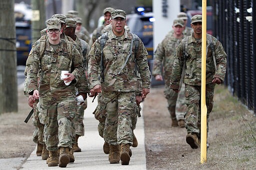 National Guard personnel march in formation as they leave duty after working Thursday, March 19, 2020, at a state-managed coronavirus drive-thru testing site that just opened on Staten Island in New York. (AP Photo/Kathy Willens)