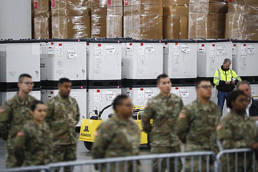 U.S. National Guard members stand beside crates of medical supplies at the Jacob Javits Center, Monday, March 23, 2020, in New York. New York City hospitals are just 10 days from running out of &quot;really basic supplies,&quot; Mayor Bill de Blasio said late Sunday. De Blasio has called upon the federal government to boost the city's quickly dwindling supply of protective equipment. The city also faces a potentially deadly dearth of ventilators to treat those infected by the coronavirus. (AP Photo/John Minchillo)