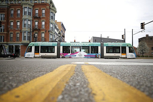 In this Tuesday, March 24, 2020 photo, a streetcar crosses Vine and 12th street in Cincinnati, on the first day of Ohio Gov. Mike DeWine's shelter-in-place order in response to the new coronavirus pandemic. All non-essential businesses are closed and residents have been asked to stay at home. (Kareem Elgazzar/The Cincinnati Enquirer via AP)